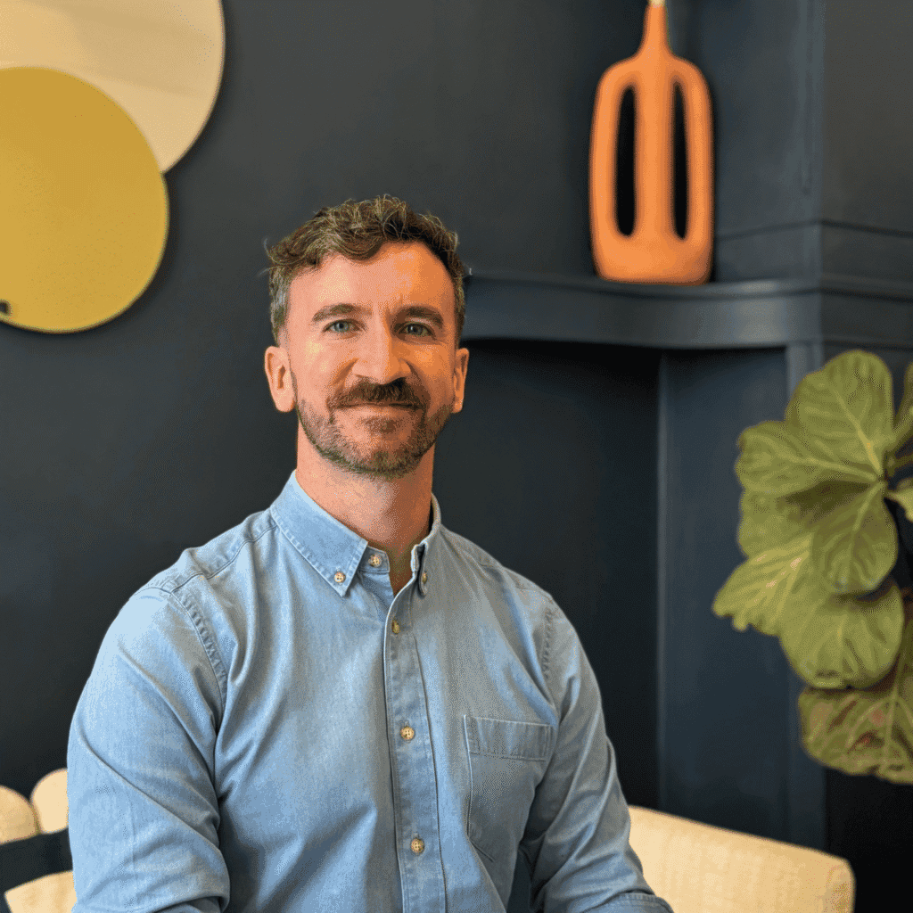 Formateur en sexocorporel France, homme souriant devant une décoration moderne.